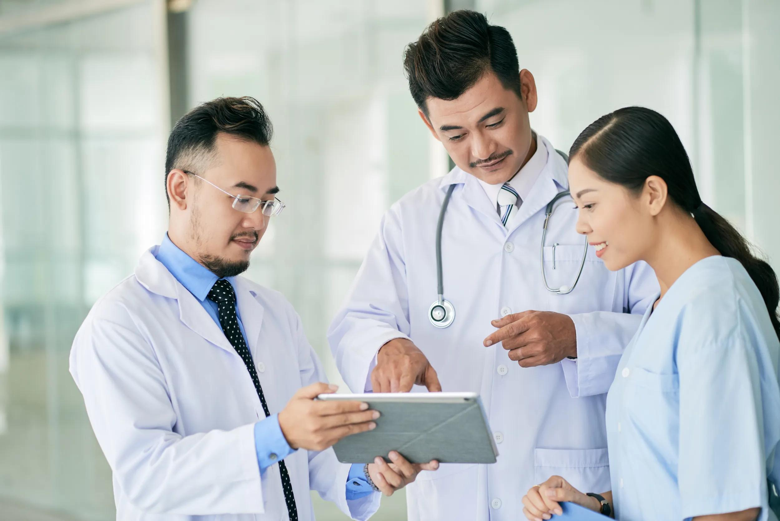 Two doctors and a nurse smiling and discussing a chart together