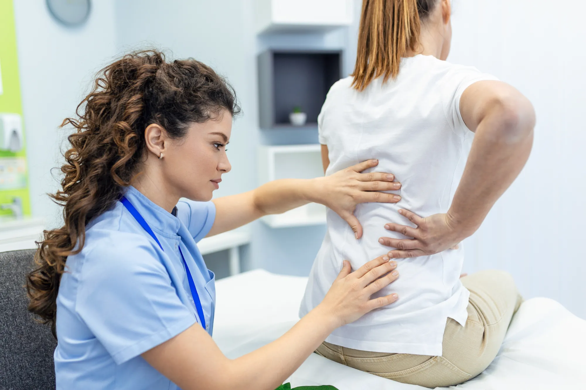 A doctor feeling a woman's lower back in physical therapy